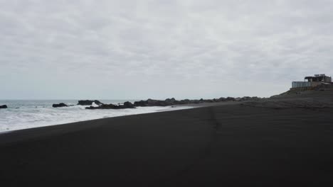 Panoramic-view-of-pichilemu-beach-with-its-black-sand-on-a-cloudy-day