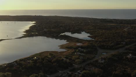 Aerial-trucking-shot-across-Montauk-Lake-and-the-Atlantic-Ocean-at-the-end-of-Long-Island-New-York-at-sunrise