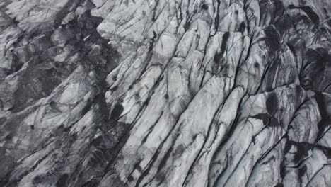 Aerial-view-around-dirty,-blackened-glacier-surface,-in-Iceland---orbit,-drone-shot