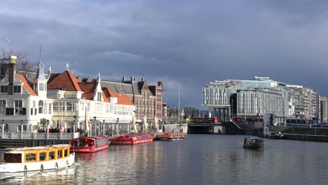 Tourist-boats-cruising-along-the-canals-in-Amsterdam-near-the-main-train-station