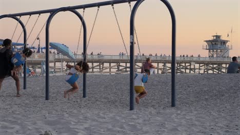An-African-American-mother-and-her-four-kids-on-a-swing-set-at-the-beach