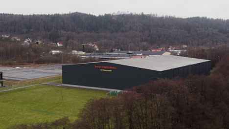 Storage-unit-building-with-green-meadow-in-small-town-of-Borås,-aerial-drone-shot