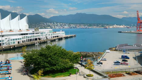 Gente-En-El-Paseo-Marítimo-Cerca-De-Canada-Place-En-Vancouver-Con-Seabus-Cruzando-La-Ensenada-De-Burrard