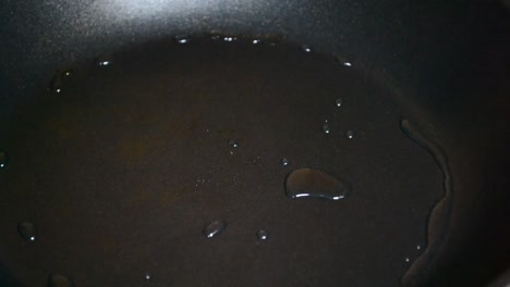 Heißes-Sojaöl-Wird-In-Einer-Schwarzen-Bratpfanne-Herumgeschwenkt,-Um-Die-Gesamte-Oberfläche-Damit-Zu-Bedecken