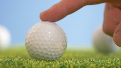 Slow-motion-shot-of-finger-rolling-white-golf-ball-on-artificial-grass-in-indoor-Golf-course---close-up