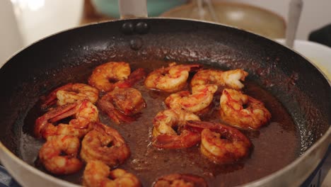 Delicious-meal-preparation,-peeled-shrimps-cooking-in-low-heat-on-a-shallow-frying-pan,-slowly-coating-and-absorbing-the-tasty-flavoursome-sweet-paprika-sauce