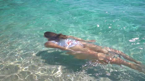 Young-woman-swimming-through-crystal-clear-water-on-a-tropical-beach