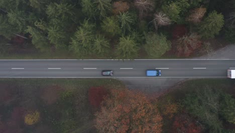 White-truck-is-driving-on-a-road,-cars-are-following,-drone-top-shot