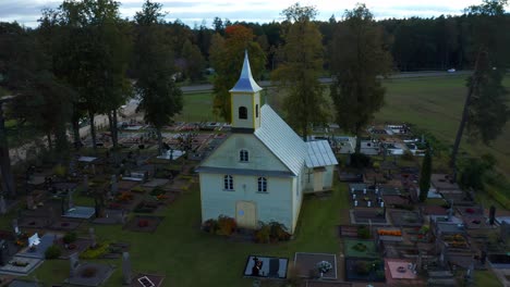 Aerial-revealing-shot-of-a-Wooden-Protestant-church-surrounded-by-a-graveyard---Lithuania