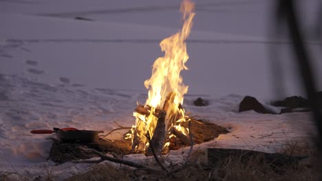 Fire-burning-in-the-snow-while-camping-with-a-pan