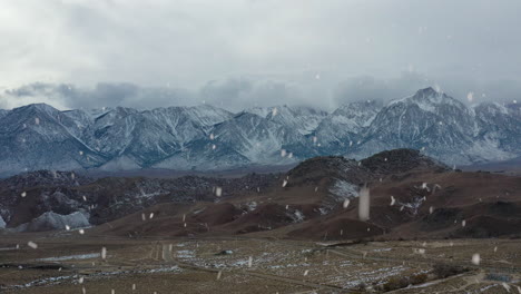 Filmischer-Blick-Auf-Die-Verschneite-Bergkette-Bei-Schneefall,-Seitlicher-Flug-Aus-Der-Luft