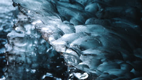 Water-drops-slowly-drip-off-melting-ice-inside-of-cave