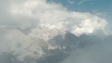 Volando-A-Través-De-Las-Nubes-Que-Revelan-El-épico-Paisaje-Montañoso-De-Los-Alpes-Austriacos-En-El-Tirol-Con-Una-Vista-Aérea-Panorámica-Y-Nubes-En-El-Cielo