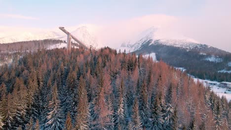 High-Tatra-amazing-mountain-snowy-landscape-with-ski-jump-tower,-aerial-forward