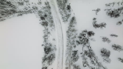 Downward-Aerial-Over-Faded-Rural-Winding-Road-In-Snowy-Winter,-Norway