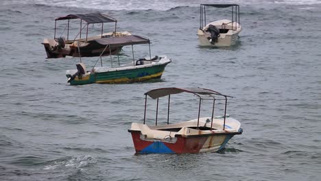 Static-view-of-four-unmanned-motor-boats-floating-in-the-troubled-water-of-the-sea-in-Hikkaduwa,-Sri-Lanka-on-Dec-2014