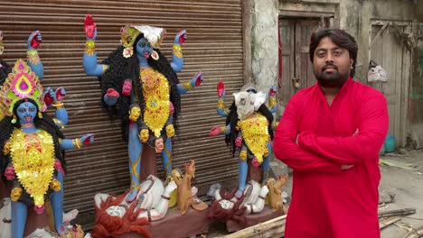 Indischer-Mann-In-Roter-Kurta-Steht-Neben-Statuen-Der-Göttin-Kali-Und-Lächelt-In-Die-Kamera,-Diwali-Fest