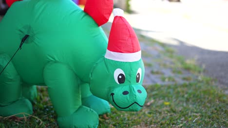 christmas-inflatable-dinosaur-with-red-hat,-christmas-garden-decoration-on-green-grass,-green-dinosaur-for-children-little-ones