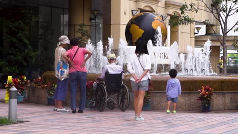 Asiatic-Chinese-people-gathering-in-front-of-a-fountain-with-fresh-water-during-a-hot-day-of-summer