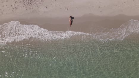 Overhead-view-of-young-bikini-woman-centered-on-beach-with-clear-water