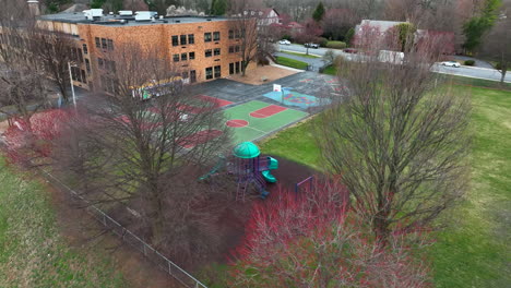 Aerial-reveal-of-school-playground-and-recess-equipment,-basketball-court