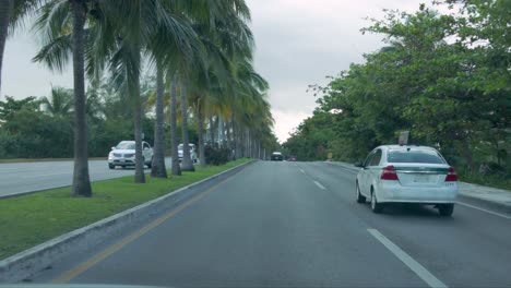 Driving-through-the-hotel-zone-on-Kukulcan-avenue-in-Cancun-Mexico-surrounded-by-palm-trees