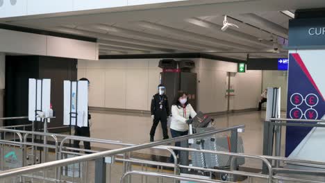 Passengers-wearing-face-masks-arrive-at-Chek-Lap-Kok-International-Airport-arrival-hall-in-Hong-Kong,-China