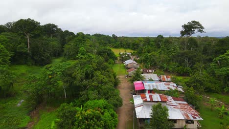 Aerial-view-moving-forward-shot,-A-community-in-the-middle-of-a-forest-in-Amazon,-Colombia,-bright-blue-sky-in-the-background