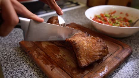 Person-cutting-roast-meat-on-wooden-board