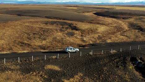 Vista-Lateral-De-Un-Automóvil-Conduciendo-A-Través-De-Un-Paisaje-Rural-Amarillo-En-Islandia