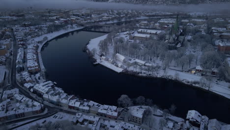 Nidarosdomen-On-Snowy-Landscape-By-The-Bank-Of-Nidelva-River-In-Trondheim-City,-Norway-At-Wintertime