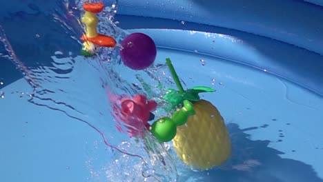 Toys-and-a-plastic-pineapple-falling-on-a-pool