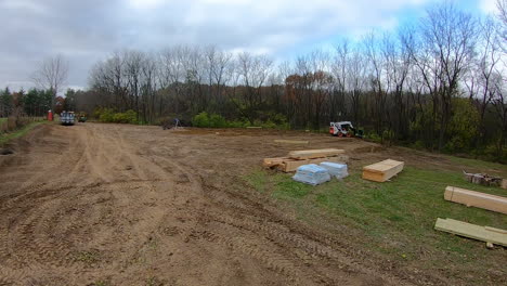 Time-lapse-of-two-men-preparing-the-ground-and-using-a-skid-steer-loader-to-dig-holes-for-the-principal-framing-poles-for-new-construction-of-a-pole-barn