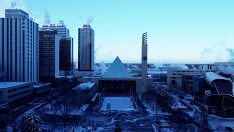 City-Hall-Edmonton-Aerial-dolly-roll-overlooking-the-free-public-outdoor-skating-ice-rink-in-the-downtown-core-on-a-cold-winter-afternoon-with-clear-blue-sky-gradations-surrounded-by-skyscrapers