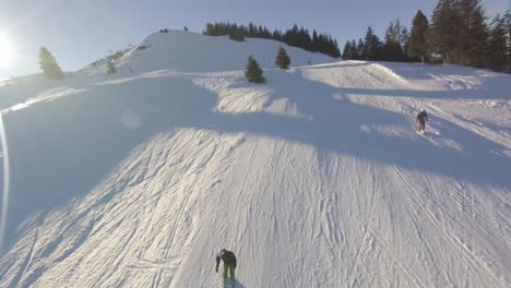 Follow-skier-ride-down-on-beautiful-swiss-resort,-aerial-fpv-drone-footage