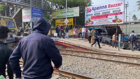 View-of-People-crossing-the-rail-tracks-in-Konnagar-Railway-station,-West-Bengal,-India-while-the-local-trains-waiting-for-departure-on-a-cold-winter-morning