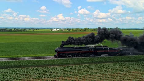 An-Aerial-Parallel-View-of-an-Antique-Steam-Passenger-Train-Traveling-With-Black-Smoke-Thru-Farmlands-on-a-Sunny-Day