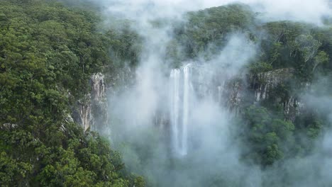 Der-Nebelbedeckte-Berg-Enthüllt-Einen-Majestätischen-Tropischen-Wasserfall,-Der-Eine-Klippe-Hinabstürzt