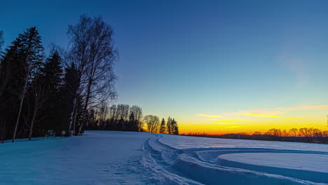 Idyllische-Schneelandschaft-Mit-Goldenem-Sonnenuntergang-Im-Hintergrund-An-Einem-Kalten-Winterabend-–-Zeitrafferaufnahme-–-Wechselnde-Farben-Am-Himmel