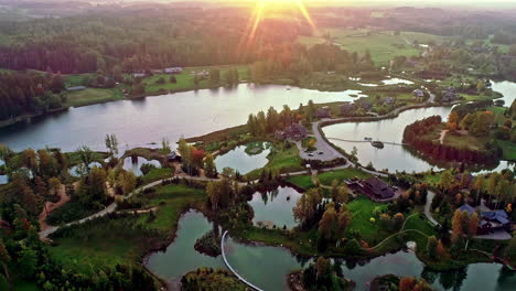 Aerial-drone-shot-of-a-beautiful-park-with-small-ponds-and-beautiful-residential-bungalows-in-upscale-neighborhood-in-the-town-at-dusk-with-sun-setting-over-the-horizon
