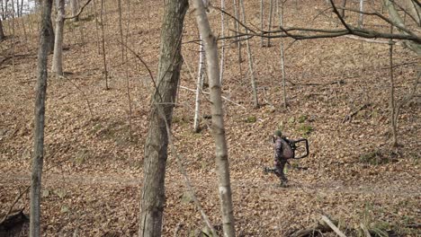 Side-view-of-bowhunter-holding-hunting-equipment-walking-on-winter-forest-path