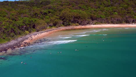 Surfers-On-The-Turquoise-Ocean-At-Noosa-Heads,-Queensland,-Australia---aerial-drone-shot