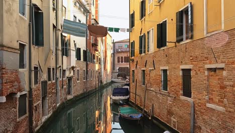Picturesque-glimpse-of-Venice-Jewish-quarter-with-boats-on-canal-and-clothes-hanging-between-houses,-Italy