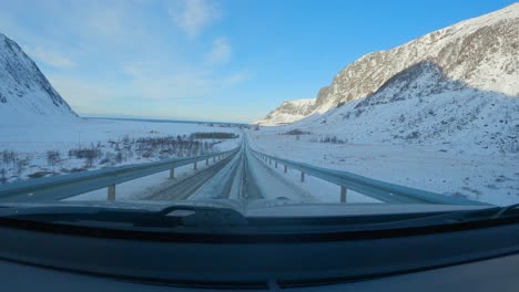 Revealing-Unstad-in-Northern-Norway-from-car-driving-in-Lofoten,-Windshield-view,-POV-car-view-slow-motion-60p