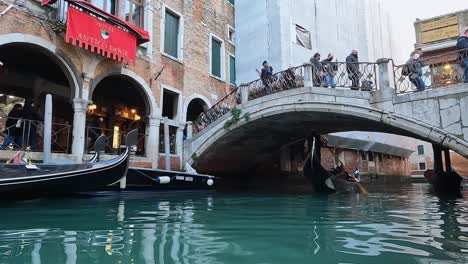 Venice-tour-with-gondola-and-gondolier-passing-under-Ponte-delle-Guglie-bridge-in-Italy
