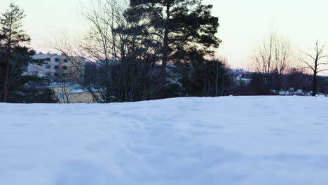 Ground-view-tilt-of-tracks-in-snow,-buildings-and-trees-in-background