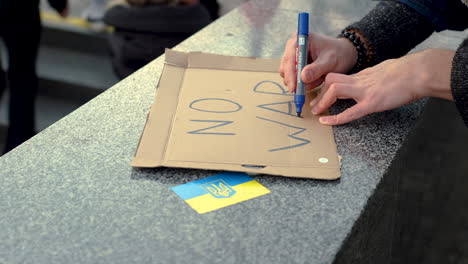 Writing-of-a-protest-sign-against-war-in-Ukraine-at-a-rally,-close-up