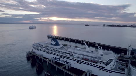 BCferries-ferryboat-docked-at-Tsawwassen-Vancouver-ferry-terminal-at-sunset,-Aerial-drone-view