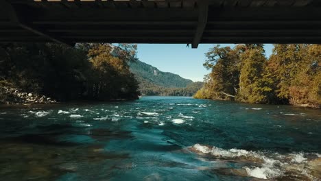 El-Dron-Pasa-Por-Debajo-De-Un-Puente-Metálico-Muy-Cerca-Del-Agua-De-Un-Río-Caudaloso.