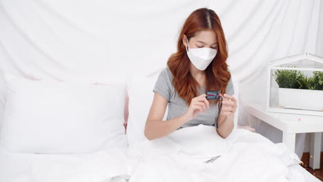 Asian-woman-with-mask-measuring-blood-oxygen-saturation-level-with-pulse-oximeter-at-home-during-the-COVID-19-pandemic-and-self-quarantine